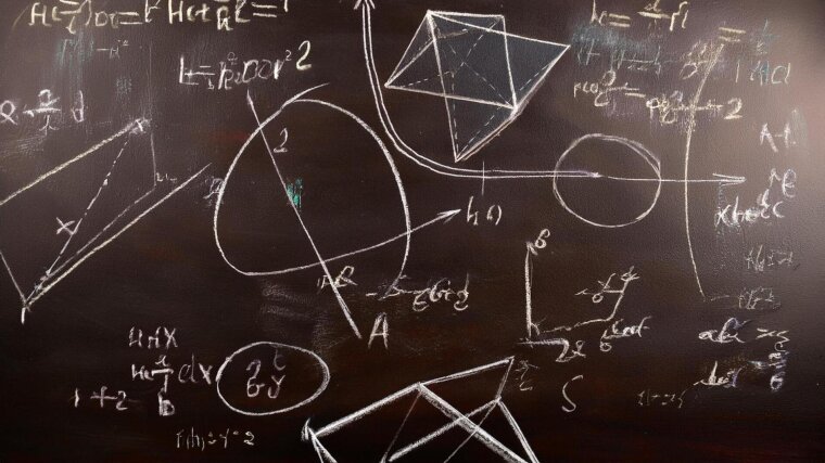 A blackboard with sketches and mathematical expressions in white chalk.