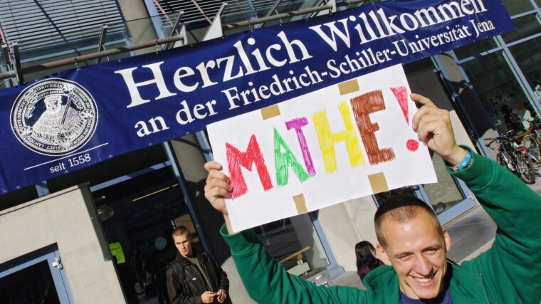 Ein Mitglied des Fachschaftsrates hält während der Studieneinführungstage ein Schild mit der Aufschrift "Mathe" hoch.