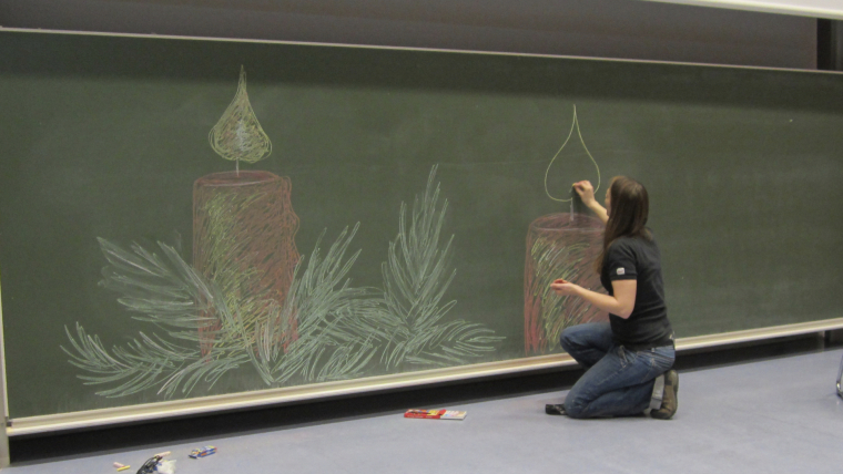 Eine Studentin bemalt die Tafel im Hörsaal mit weihnachtlichen Motiven